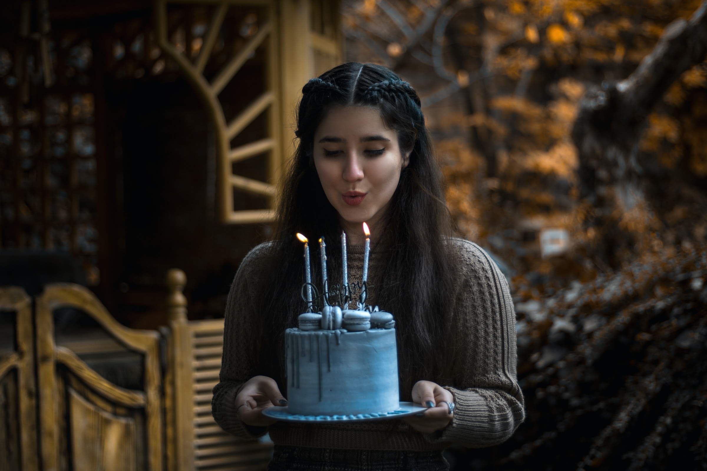 девушка задувает свечи на праздничном торте