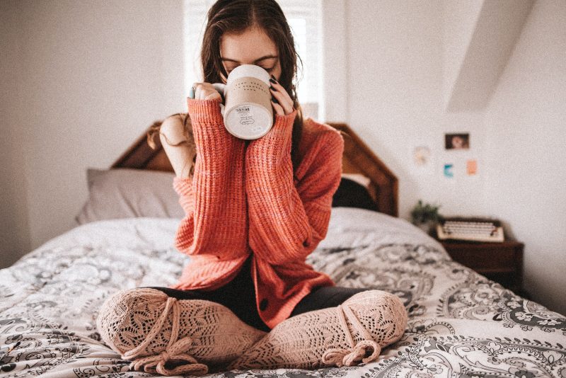 Девушка завтракает чашкой кофе в постели