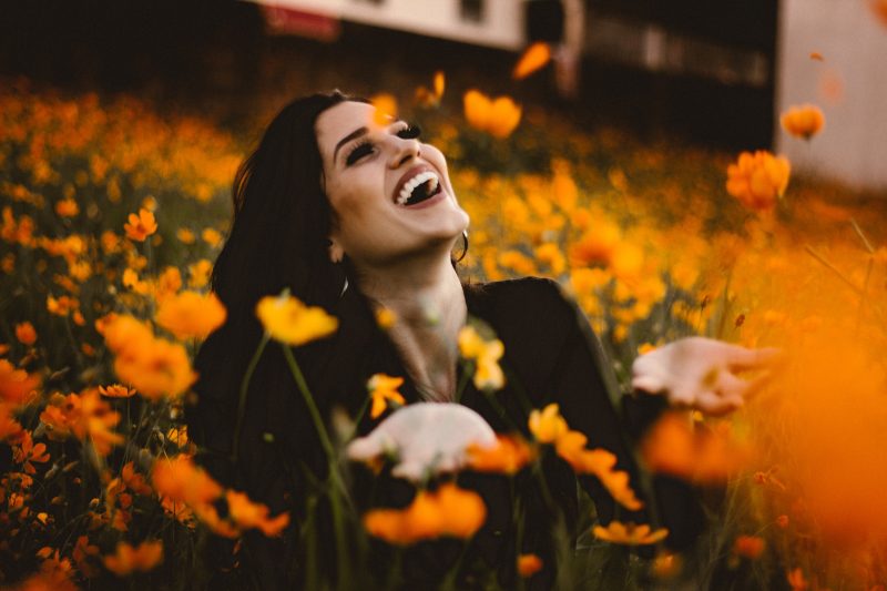 Девушка смеется в поле цветов